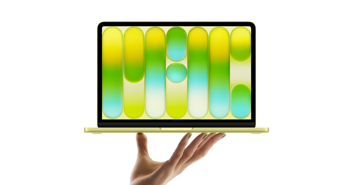 MacBook Neo i sitrus holdes oppe av en hånd